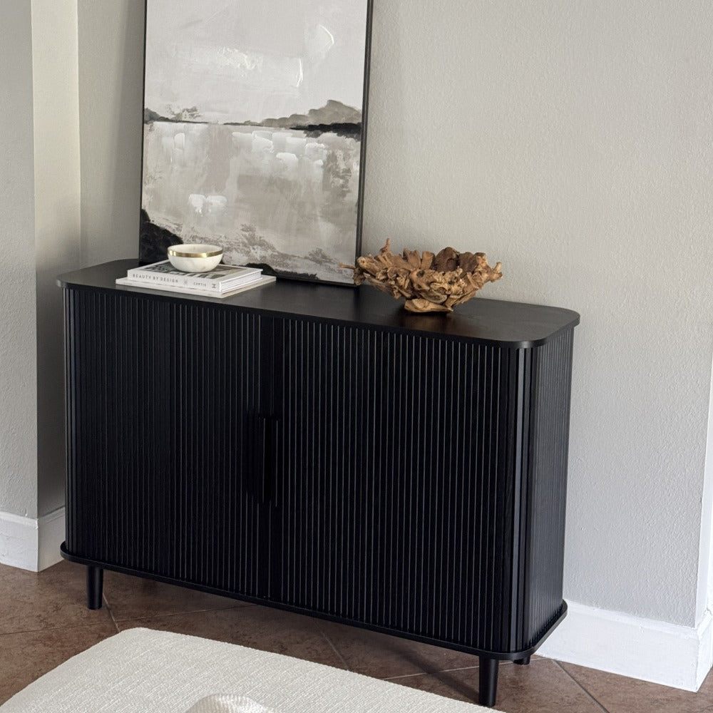 Black sideboard with decorative items against a gray wall