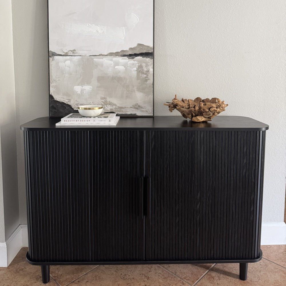 Black ribbed sideboard with decorative items against a white wall