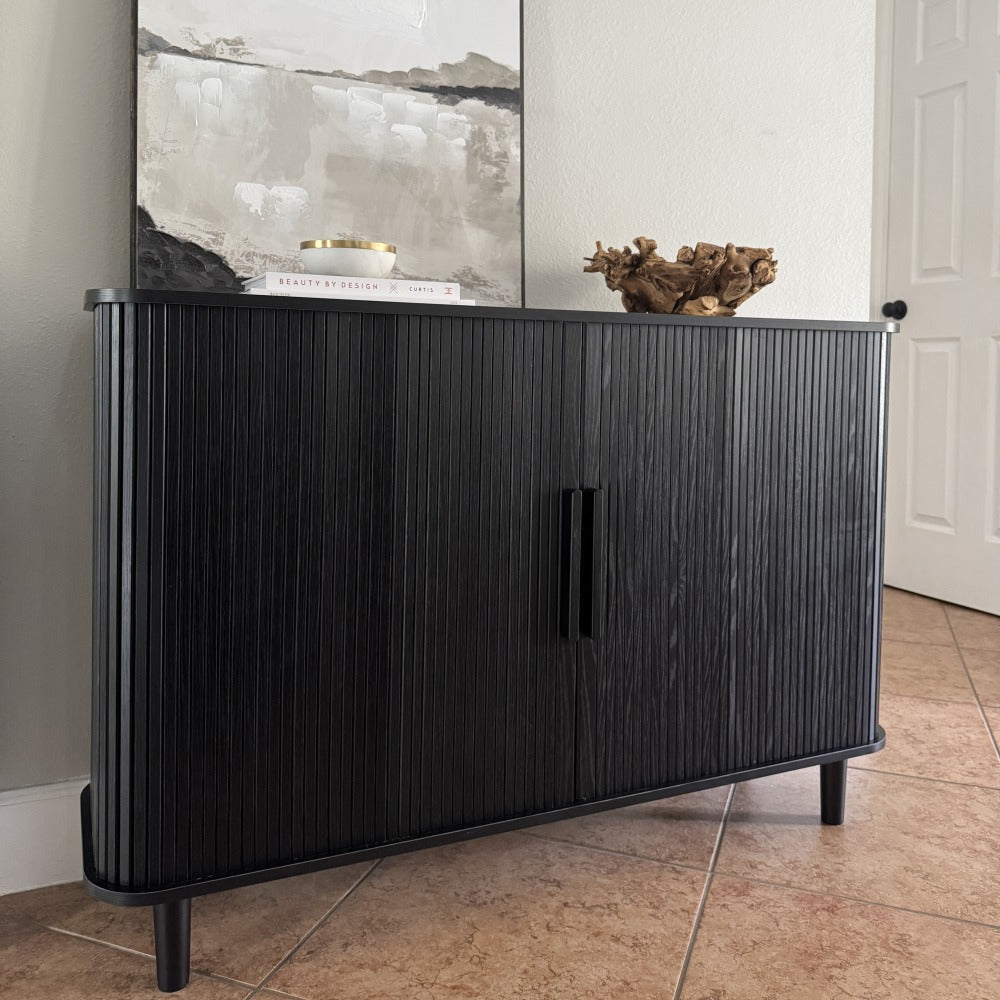 Black sideboard with decorative items against a neutral wall.