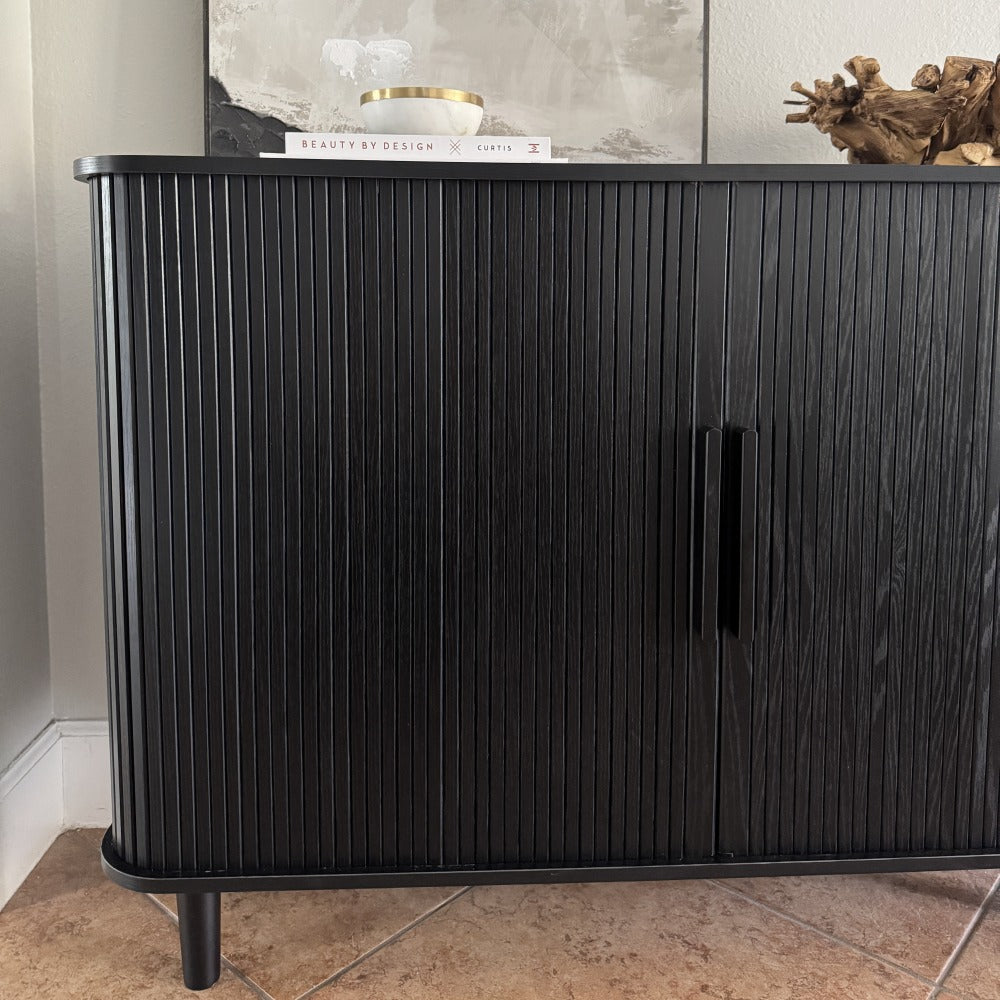 Black ribbed sideboard with decorative items on a neutral background