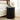 Black ribbed side table with a lamp and clock next to a white sofa in a bedroom.