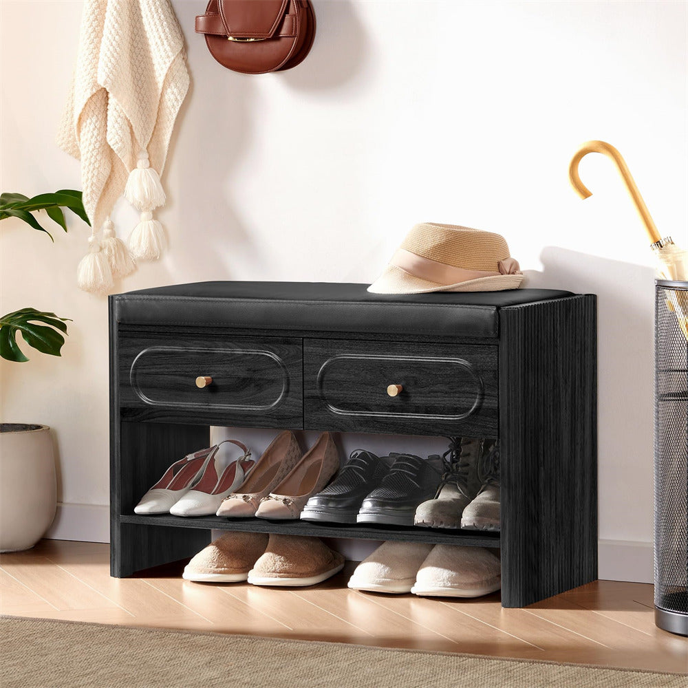 Black shoe storage bench with shoes underneath, against a white wall.