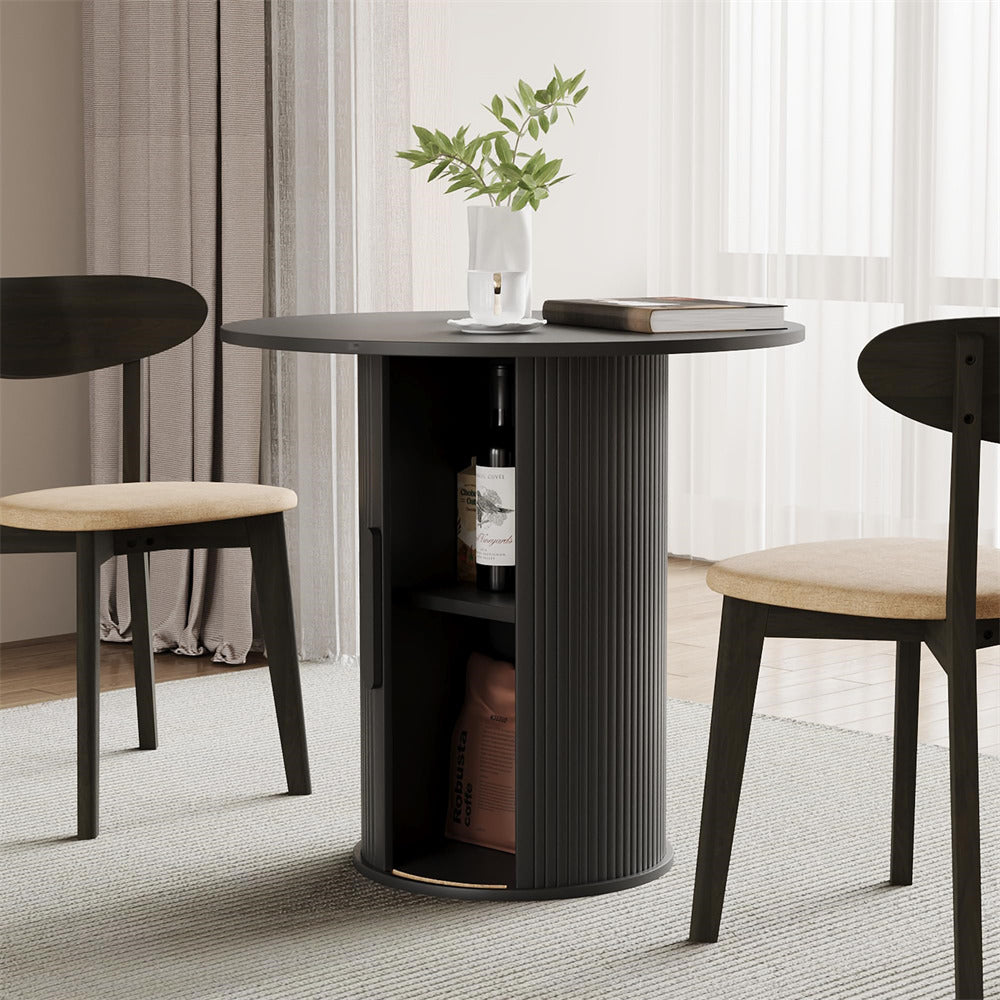 Round black dining table with two chairs in a room with curtains and a plant.