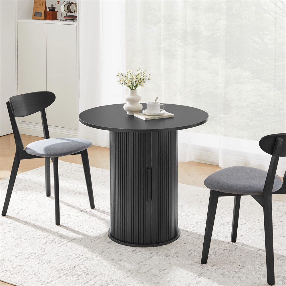 Black round table with two chairs in a room with white curtains and a rug.