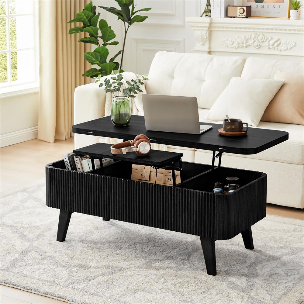 Black lift-top coffee table in a living room setting with a laptop, books, and decorative items.