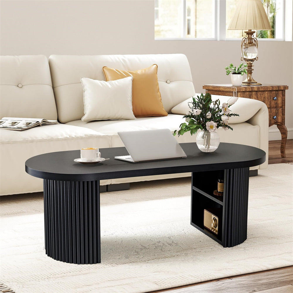Black coffee table with a laptop, cup, and flowers in a living room setting.