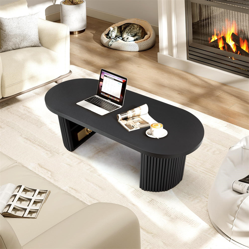 Black coffee table with laptop and newspaper in a living room with a fireplace.