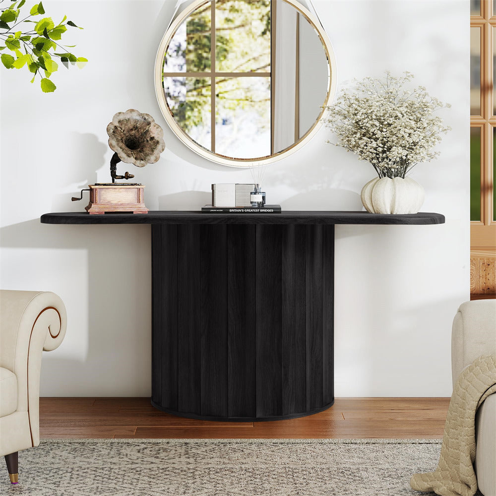 Black round table with decorative items in a room with a mirror and plants.