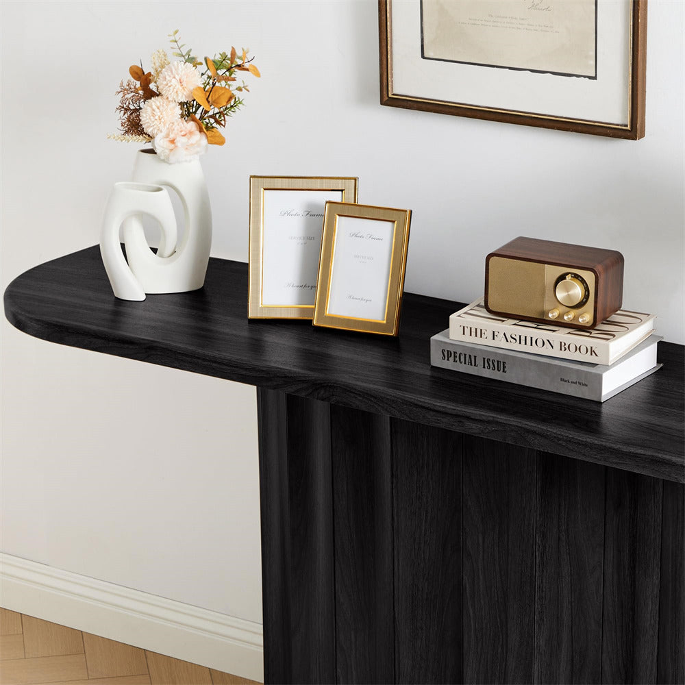 Decorative setup on a black console table with books, a vase, and framed pictures.