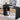 Black L-shaped desk with storage shelves, computer setup, and decor items in a room.