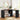 Black L-shaped desk in a room with a mirror, stool, and decorative items.