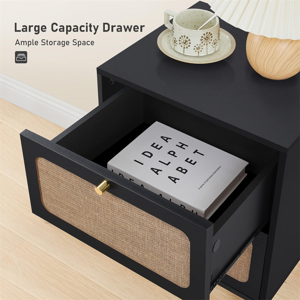 Black nightstand with open drawer containing a book, cup, and saucer on a light wood floor.