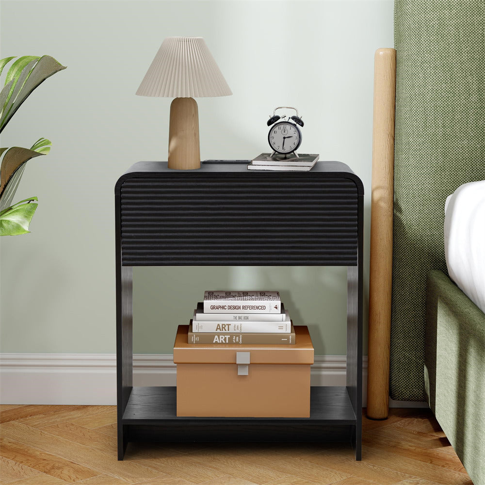 Black nightstand with lamp, clock, and books in a bedroom setting