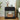 Black nightstand with lamp, clock, and books in a bedroom setting