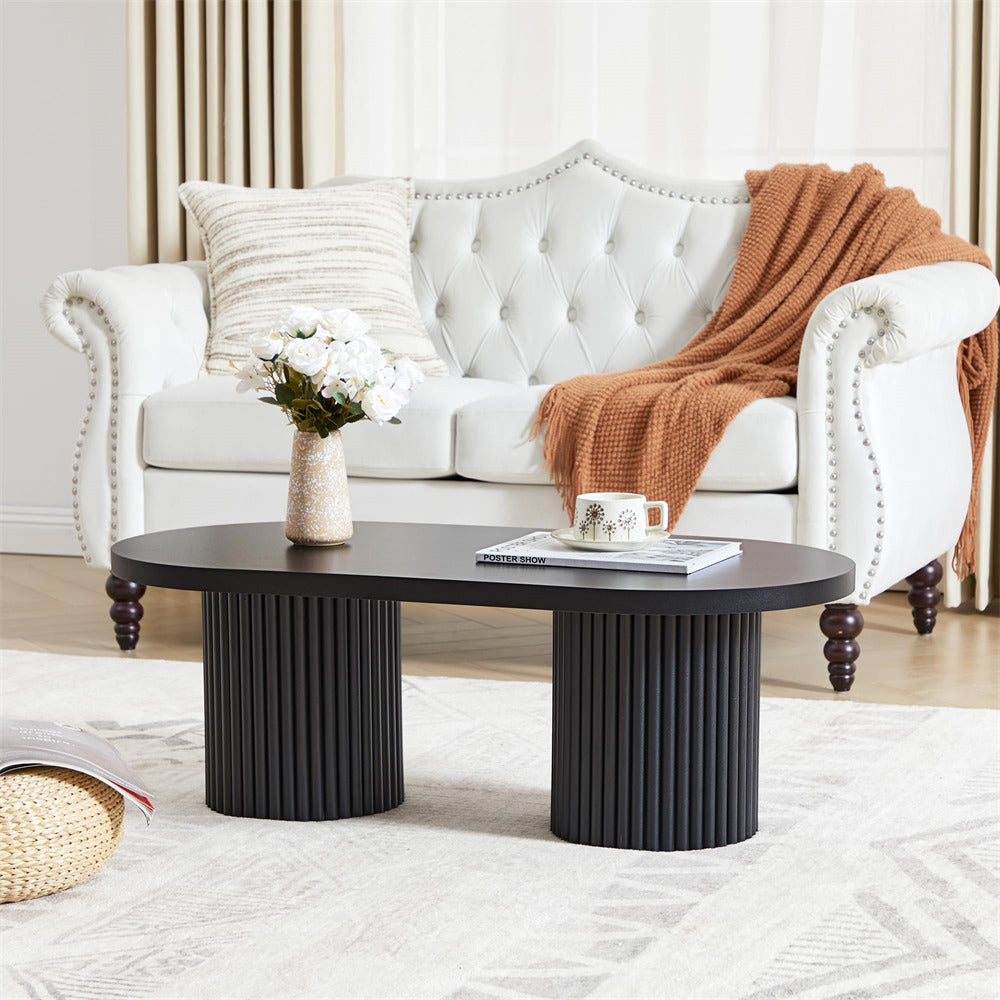 Black coffee table in front of a white sofa with a brown throw blanket in a living room setting.