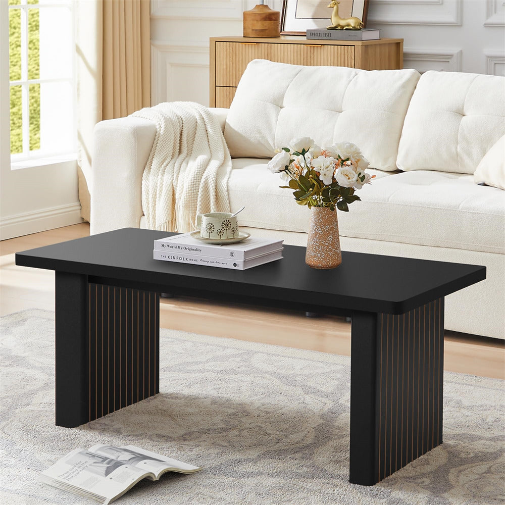 Black coffee table with books and a vase in a living room setting