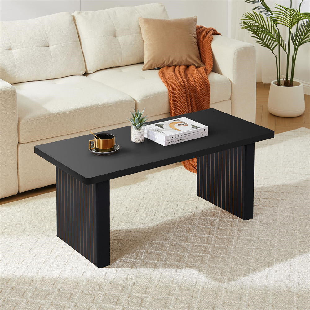 Black coffee table with a cup and books in a living room setting