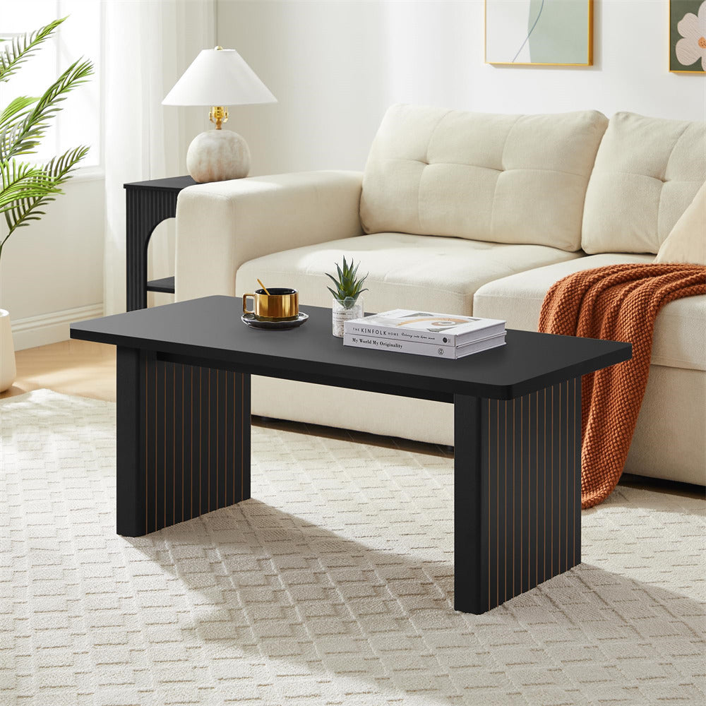 Black coffee table in a living room with a beige sofa and decorative items.