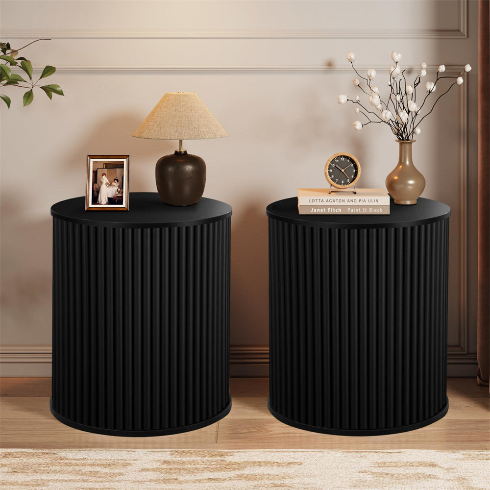 Two black cylindrical side tables with decorative items in a room setting.