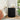 Black pleated side table with lamp and decor items in a bedroom setting