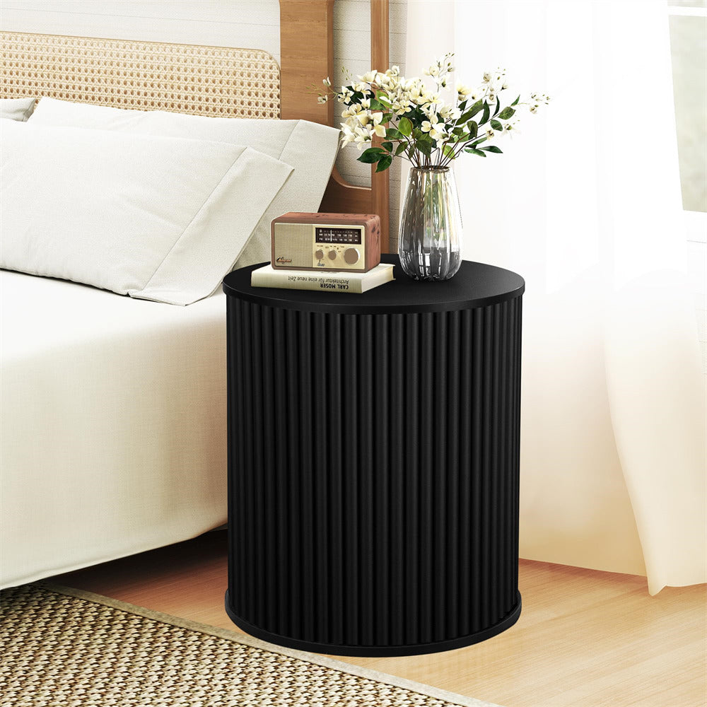 Black ribbed side table with a vase of flowers and radio in a bedroom setting