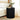 Black ribbed side table with a vase of flowers and radio in a bedroom setting