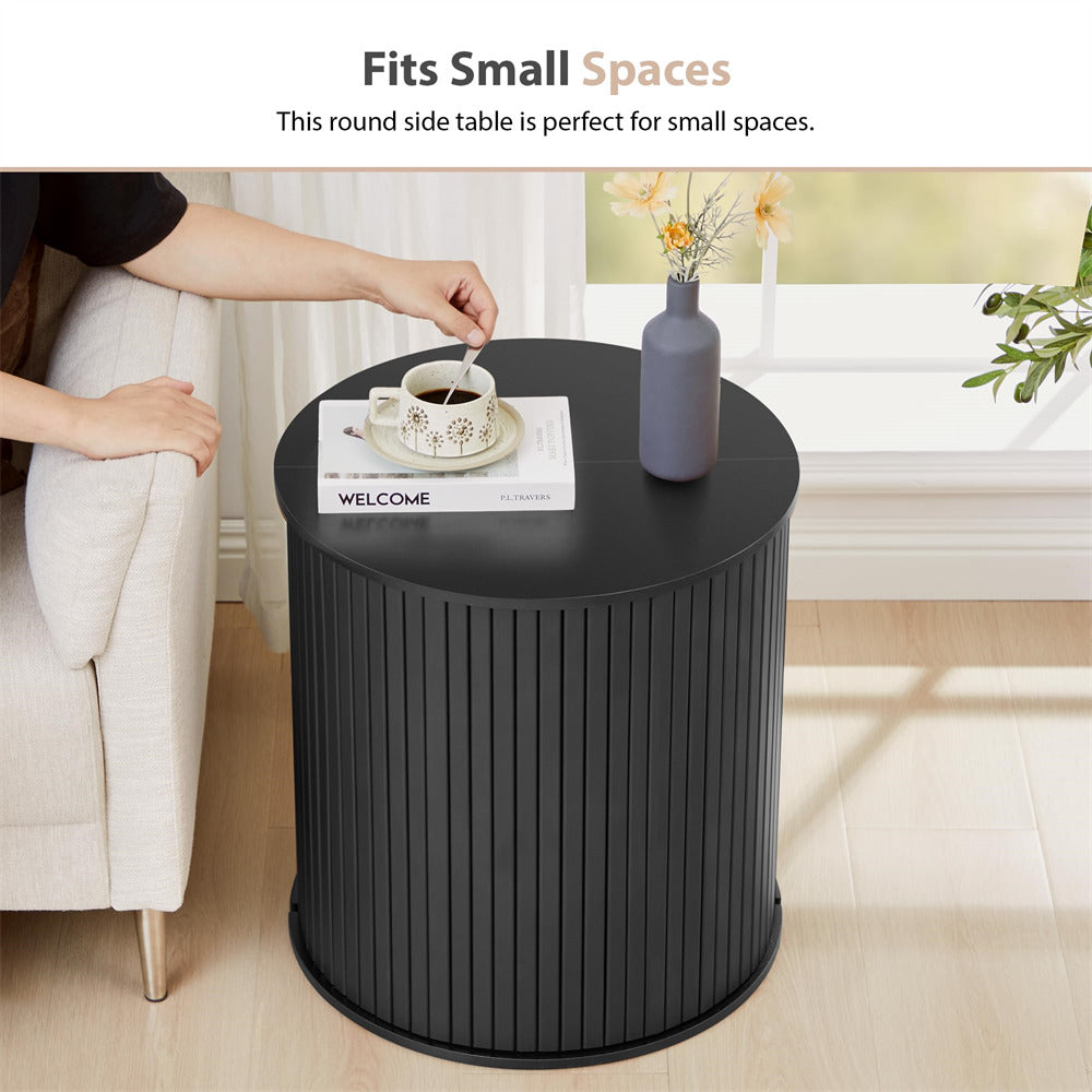 Black round side table in a living room setting with a person placing a cup on it.