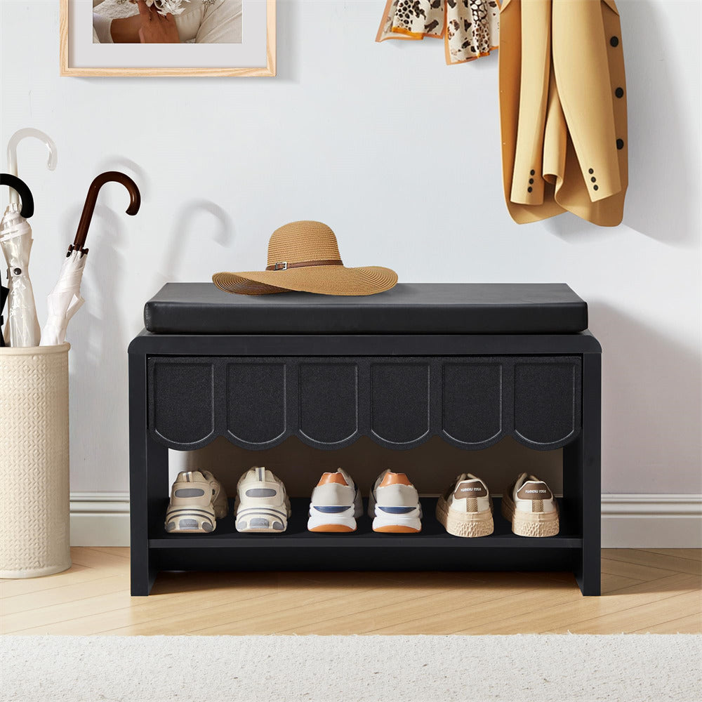 Black shoe storage bench with shoes underneath, hat on top, against a light gray wall.