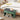 Green bench with storage drawers next to a bed with white bedding and decorative pillows.