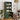 Green bookshelf with kitchen appliances in a room with wooden chairs and a table.