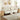 Beige sectional sofa in a living room with wooden side tables and abstract art on the wall.