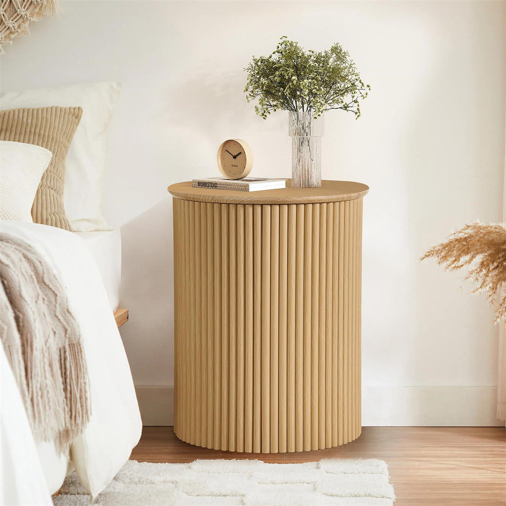 Beige side table with decorative items next to a bed in a bedroom setting