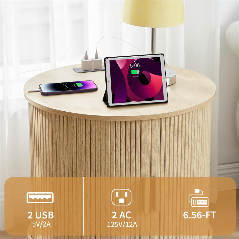 Round wooden side table with electronic devices on top, including a tablet and smartphone, with cable management.