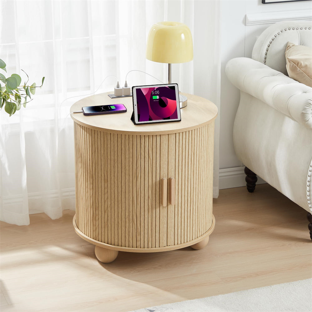 Round wooden side table with a lamp, phone, and tablet in a living room setting.