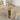Round wooden table with shelves, fruit bowl, and flowers in a room setting.