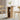 Wooden dining table with storage shelves and two chairs in a room with curtains.