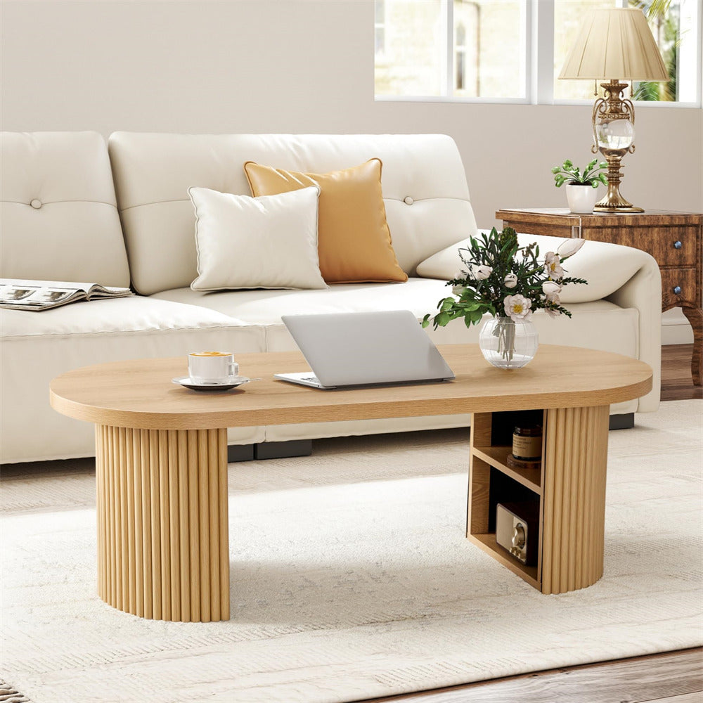 Wooden coffee table with a laptop, mug, and flowers in a living room setting.