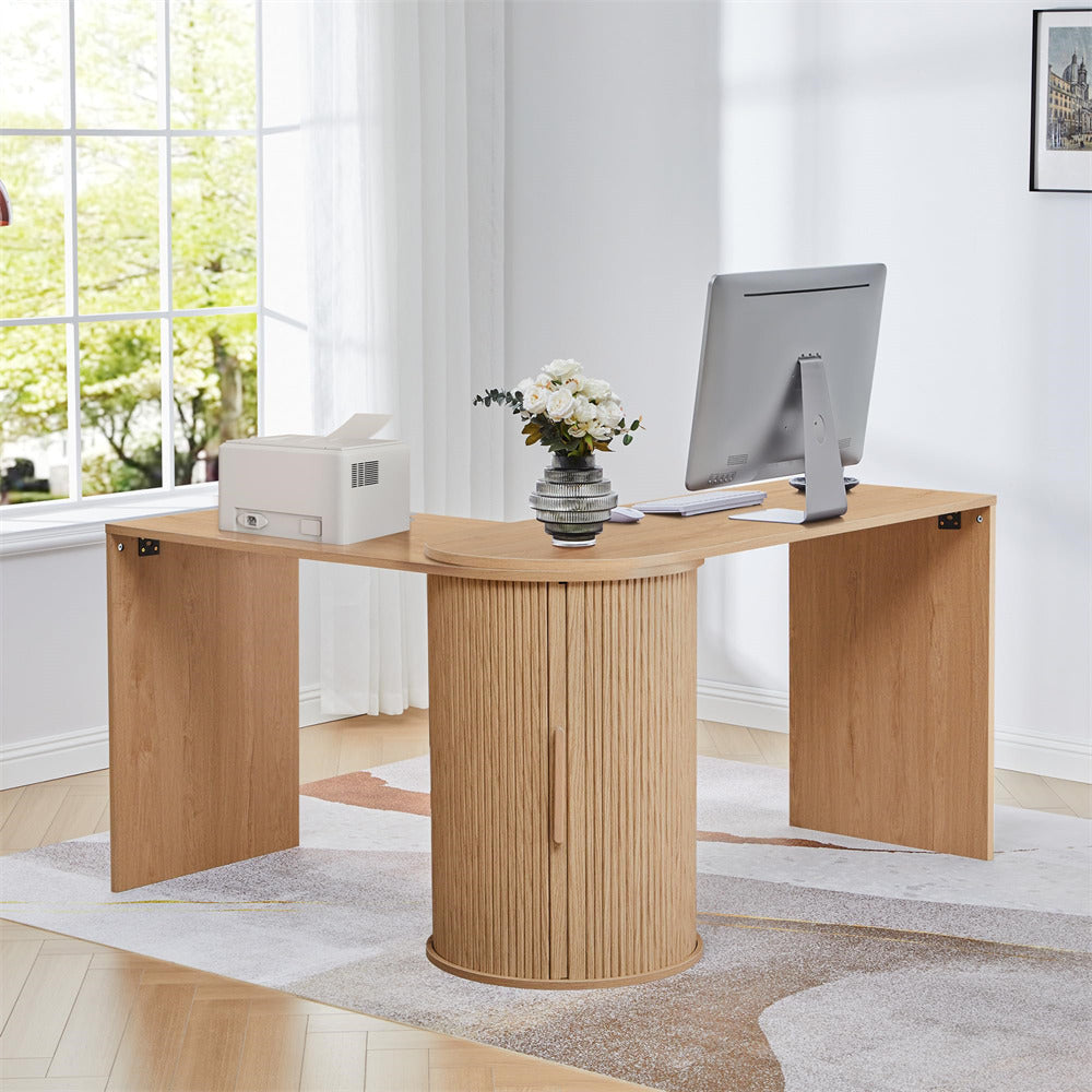 Wooden L-shaped desk with a computer monitor, keyboard, and printer in a bright room.