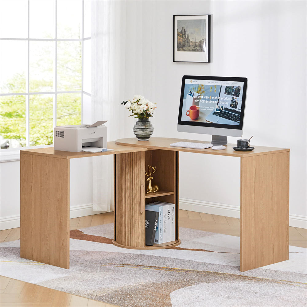 Wooden L-shaped desk with a computer setup in a bright room.