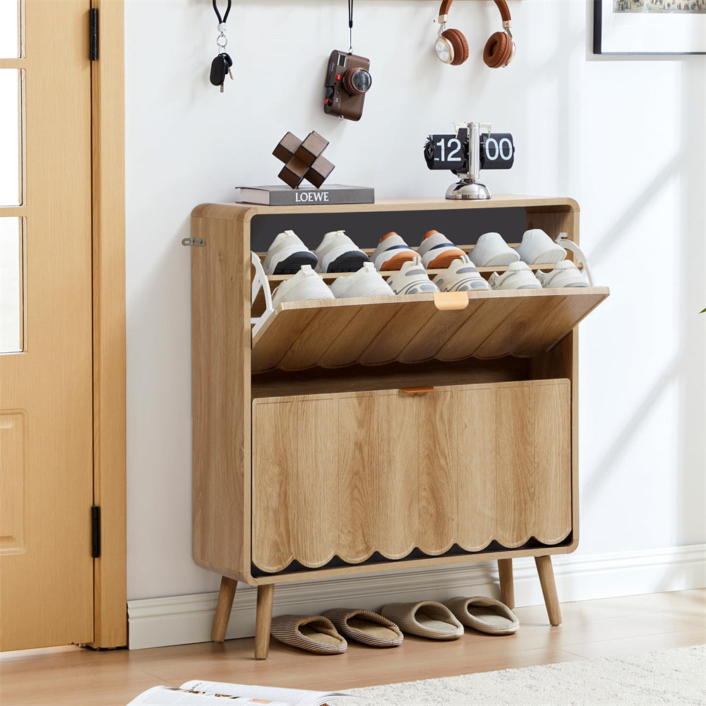 Wooden shoe cabinet with open door displaying shoes, slippers on the floor, and decor items on a white wall.