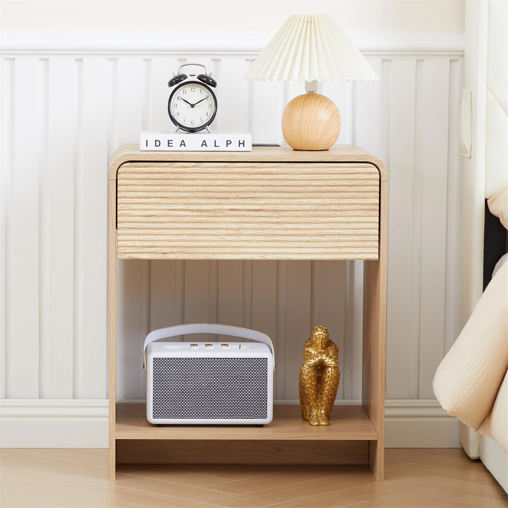 Wooden nightstand with decorative items including a clock, lamp, and speaker in a bedroom setting.