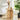 Wooden side table with decorative items next to a white armchair in a bright room.
