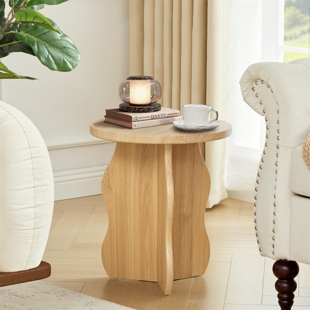Wooden side table with a candle, books, and a cup in a living room setting.