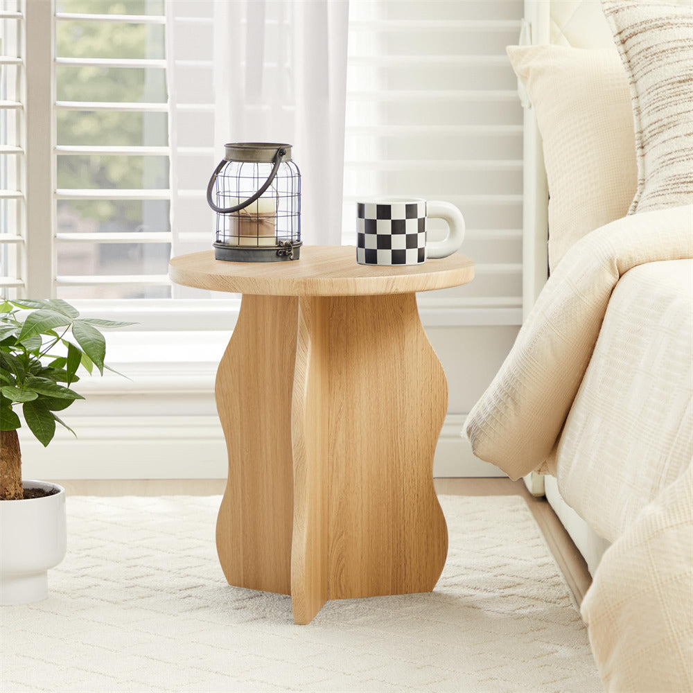 Wooden side table with a mug and lantern next to a bed in a bedroom.