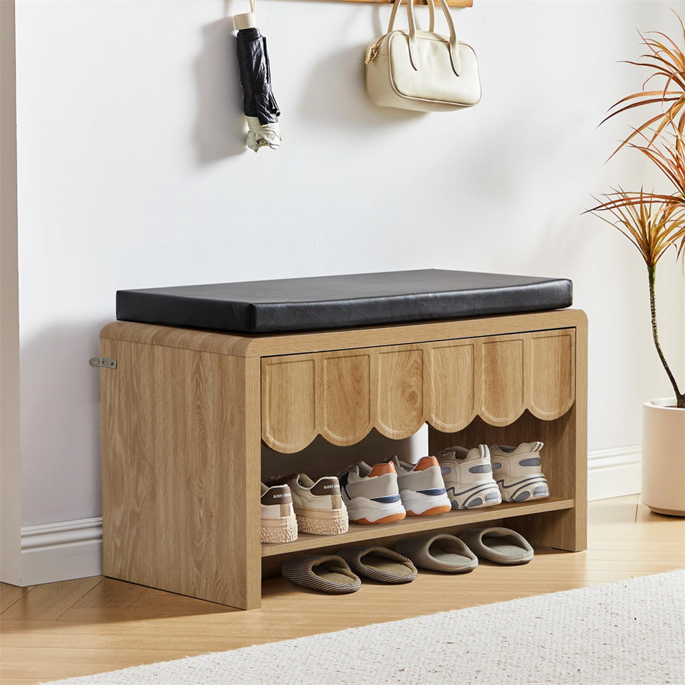 Wooden shoe storage bench with black cushioned top and open shelf displaying shoes, with a plant in the background.