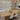 Dining room with wooden table, lace runner, and white chairs.