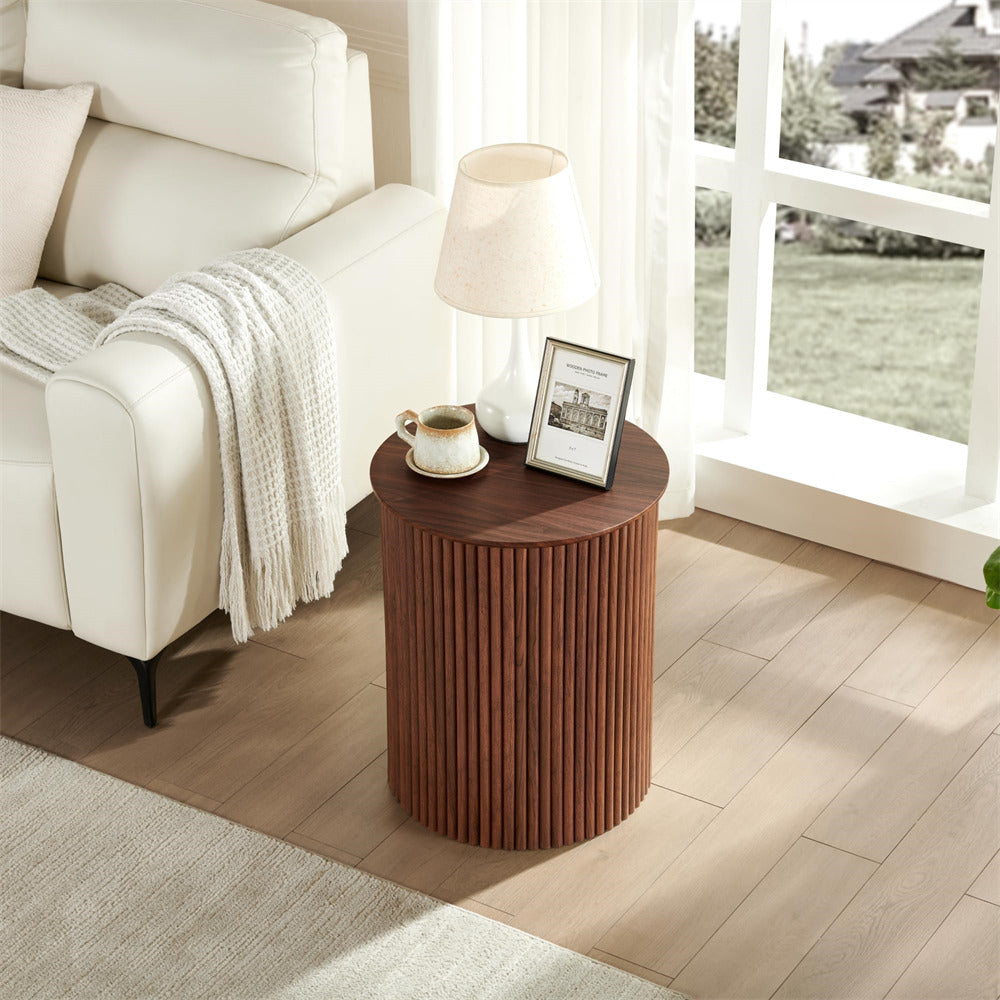 Wooden side table with a lamp and picture frame next to a white sofa in a bright room.