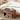 Wooden nightstand with black cushion next to a bed with white bedding and yellow pillows.