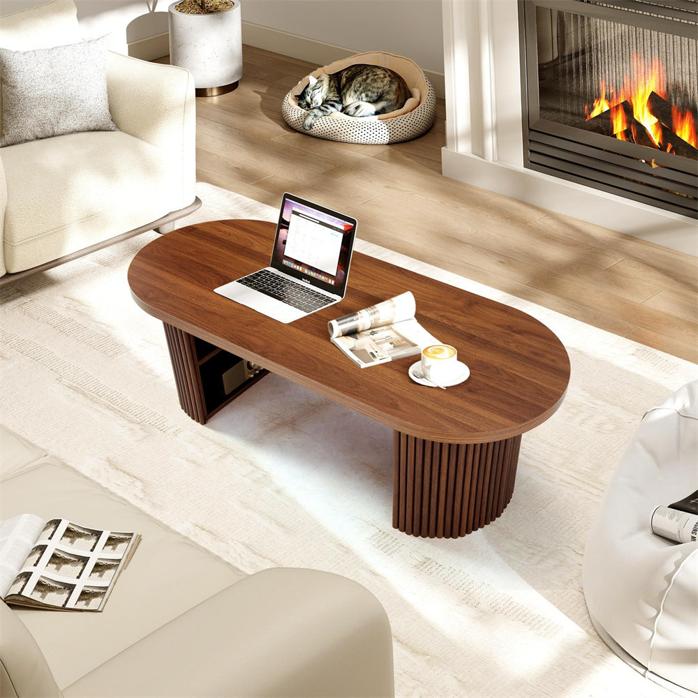 Wooden coffee table with laptop and newspaper in a living room with a fireplace.