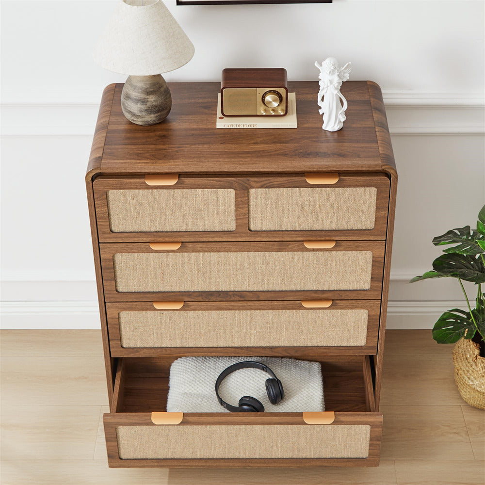 Wooden dresser with open drawer containing headphones, on a light wooden floor with a plant in the corner.